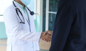 medico stretta mano camice covid